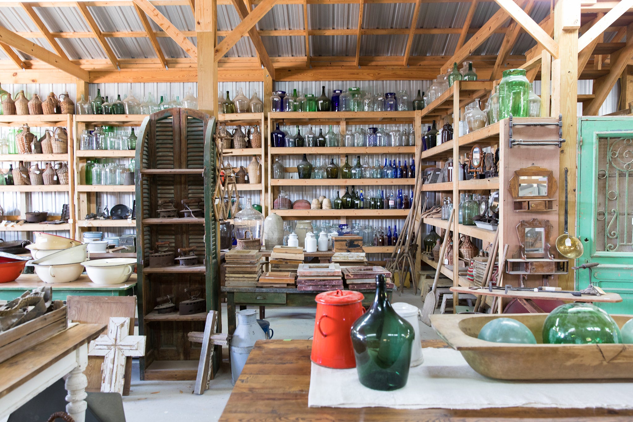 Interior of a rustic store with wooden shelves filled with jars, bottles, and other items.